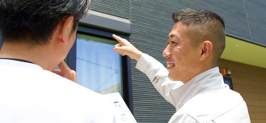 外壁を指差してお客様とお話ししている様子